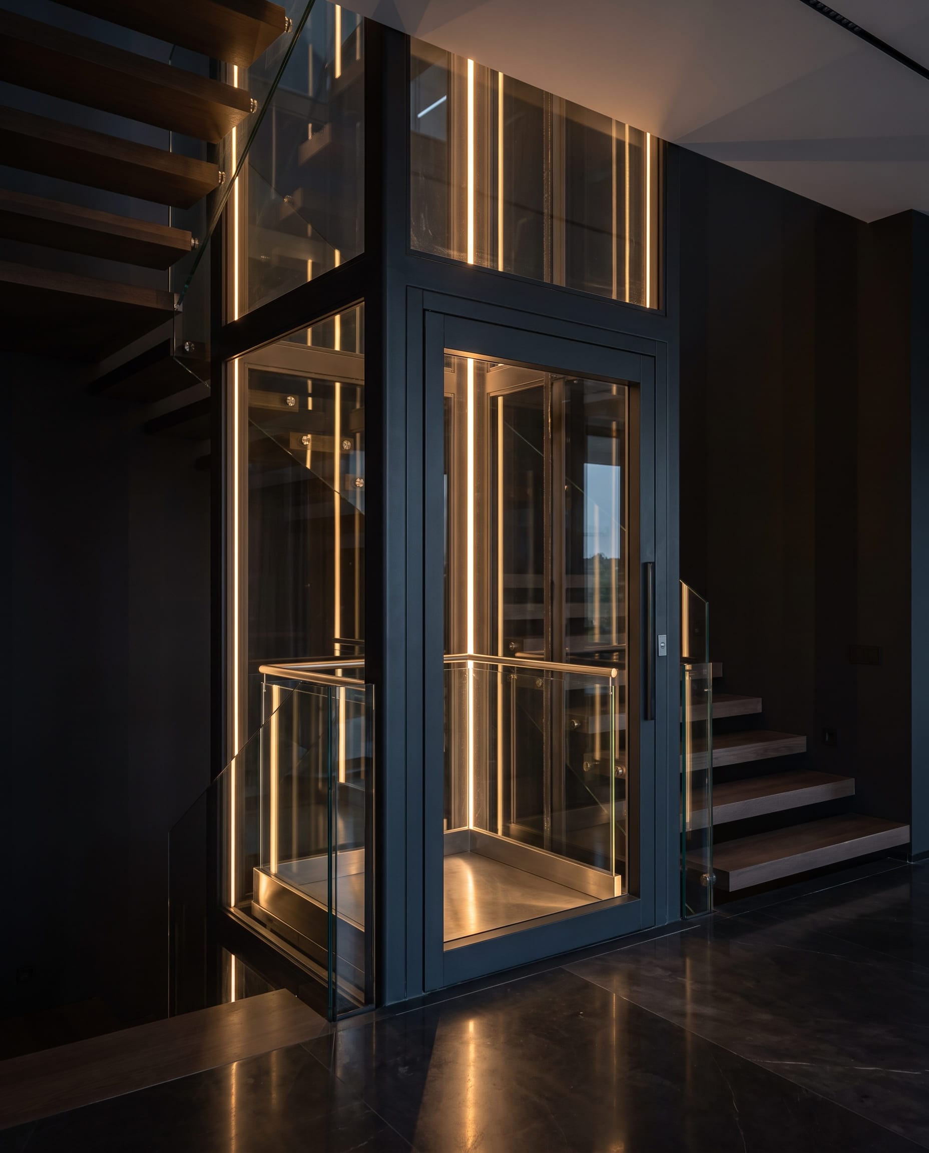 Piattaforma elevatrice con vano interamente vetrato in una villa minimalista, struttura in acciaio antracite